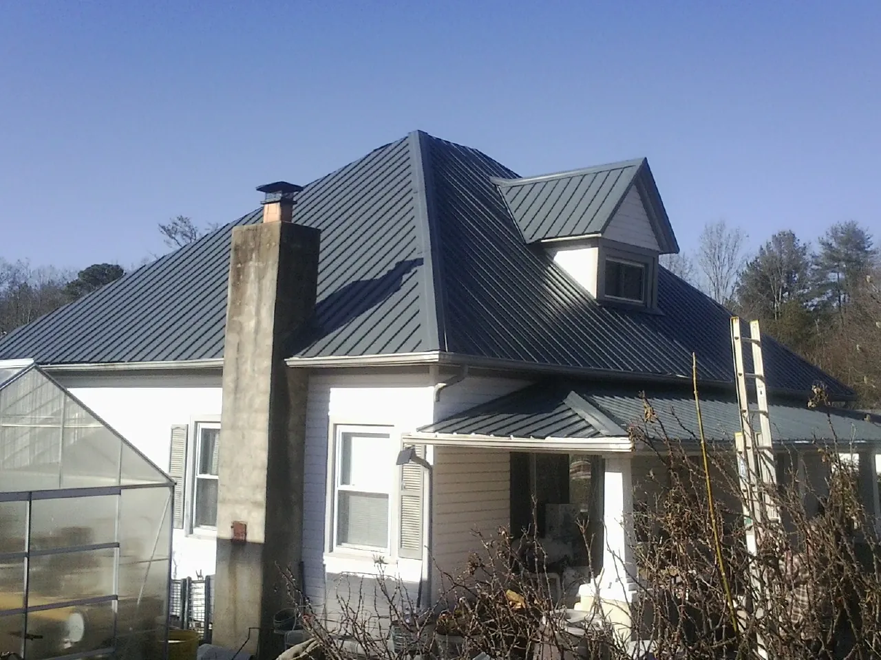 Dark blue standing seam metal roof on a white farmhouse with dormer — Slate & Tile Roof Repair by Roofing Brothers in Windsor